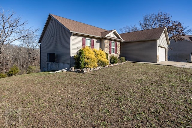 view of front of property featuring a front yard, central AC, and a garage