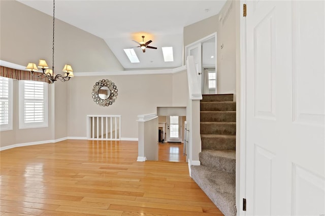 entrance foyer with ceiling fan with notable chandelier, lofted ceiling, crown molding, and light hardwood / wood-style flooring