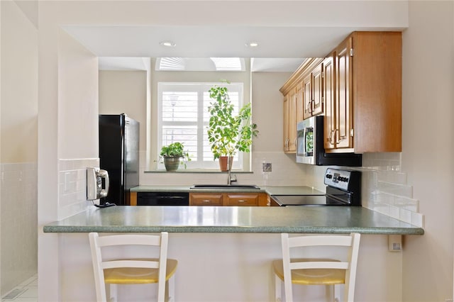 kitchen with a kitchen breakfast bar, decorative backsplash, sink, and black appliances