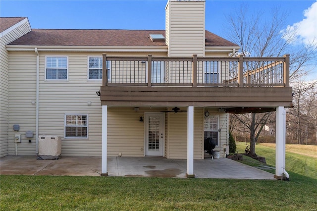 rear view of property featuring a lawn, a wooden deck, and a patio