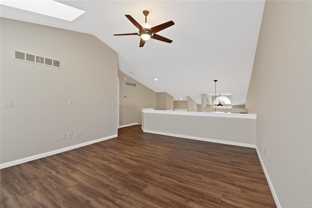 unfurnished living room featuring ceiling fan, lofted ceiling with skylight, and dark wood-type flooring