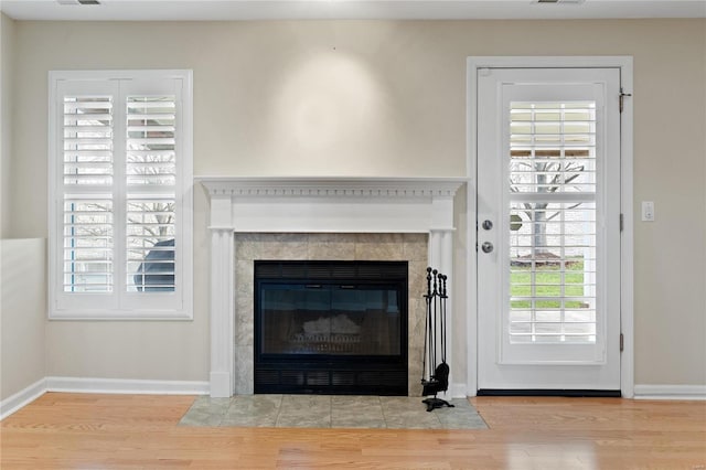 living room featuring a tile fireplace, light wood-type flooring, and a healthy amount of sunlight