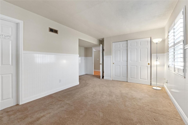 unfurnished bedroom featuring a closet and light colored carpet