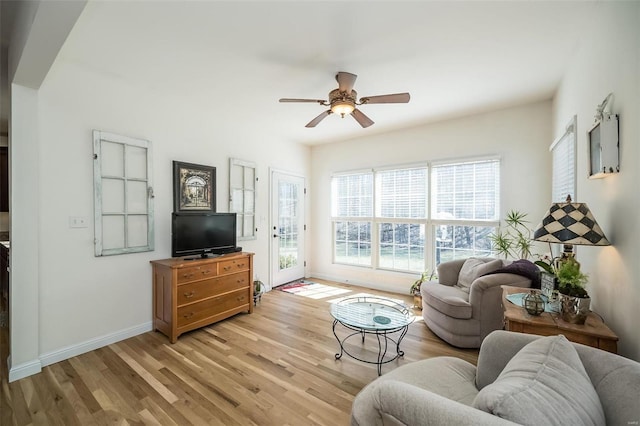 living area with light wood-style flooring, a ceiling fan, and baseboards