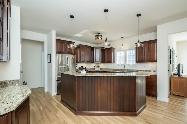 kitchen with a kitchen island, dark brown cabinetry, stainless steel fridge with ice dispenser, and light wood finished floors