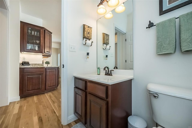 bathroom with toilet, wood finished floors, and vanity