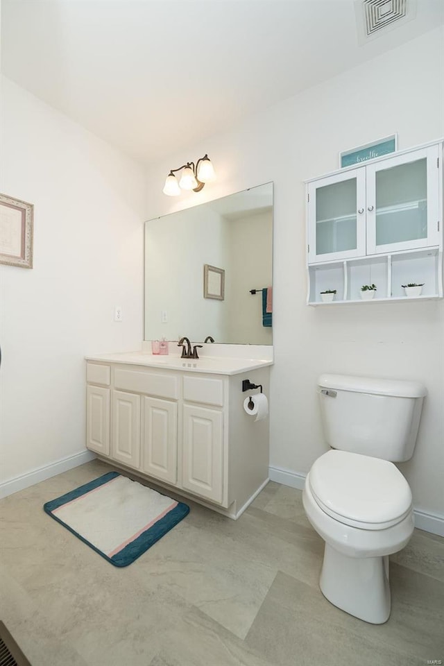 bathroom featuring vanity, toilet, baseboards, and visible vents