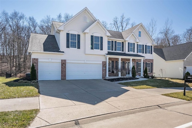 traditional-style house featuring roof with shingles, driveway, a porch, a front lawn, and brick siding