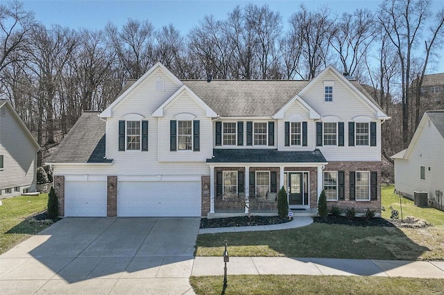 traditional-style house with a front lawn, central air condition unit, brick siding, and driveway