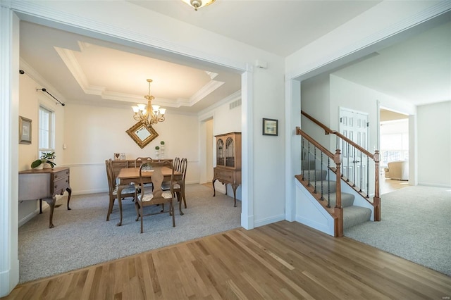 dining space with a wealth of natural light, a tray ceiling, light wood-style floors, and stairway