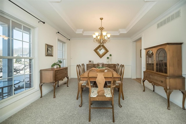 dining room with visible vents, an inviting chandelier, a tray ceiling, ornamental molding, and light colored carpet