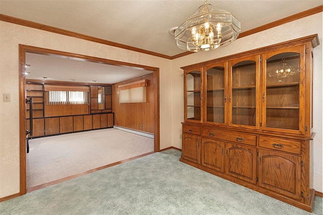 unfurnished dining area with light carpet, a notable chandelier, a textured ceiling, crown molding, and a baseboard heating unit