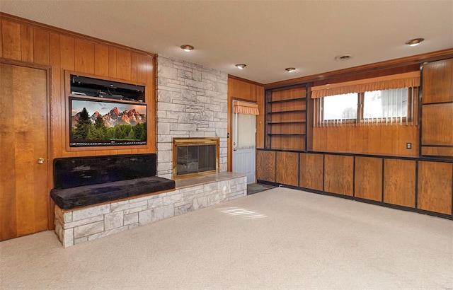 living room with a fireplace, light colored carpet, wooden walls, and ornamental molding