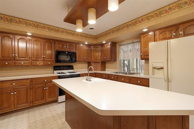 kitchen featuring white appliances, sink, and an island with sink