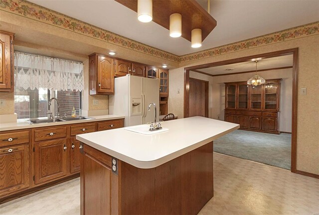 kitchen featuring a chandelier, sink, white fridge with ice dispenser, a kitchen island, and pendant lighting