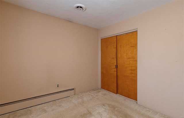 unfurnished bedroom featuring a closet, a textured ceiling, light colored carpet, and a baseboard radiator