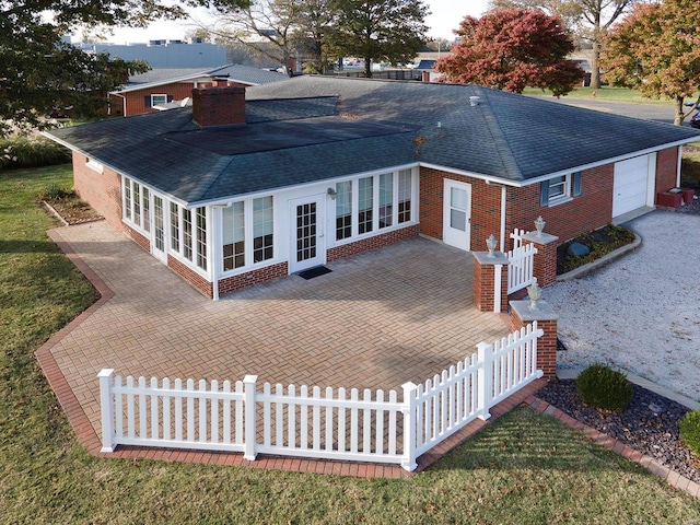 rear view of property featuring a garage and french doors