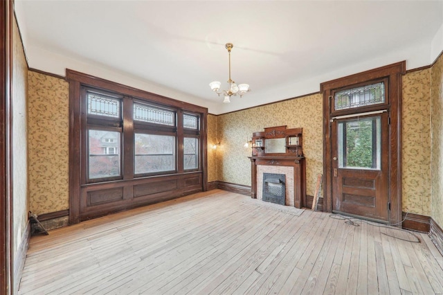 unfurnished living room featuring a chandelier and light hardwood / wood-style flooring