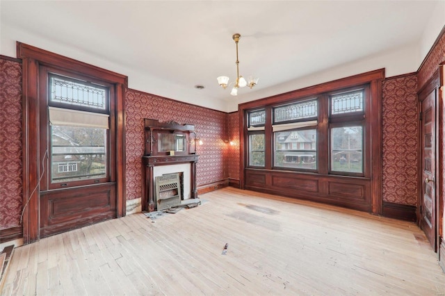 unfurnished living room with a chandelier and light wood-type flooring