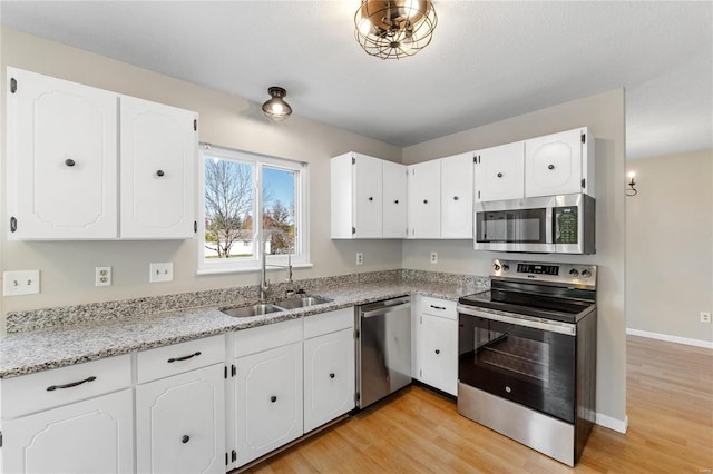 kitchen with white cabinets, light hardwood / wood-style floors, sink, and appliances with stainless steel finishes