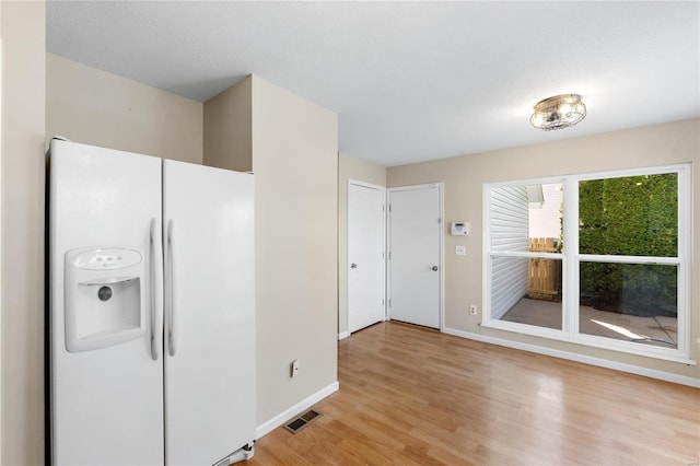 kitchen with light hardwood / wood-style floors, white refrigerator with ice dispenser, and a textured ceiling