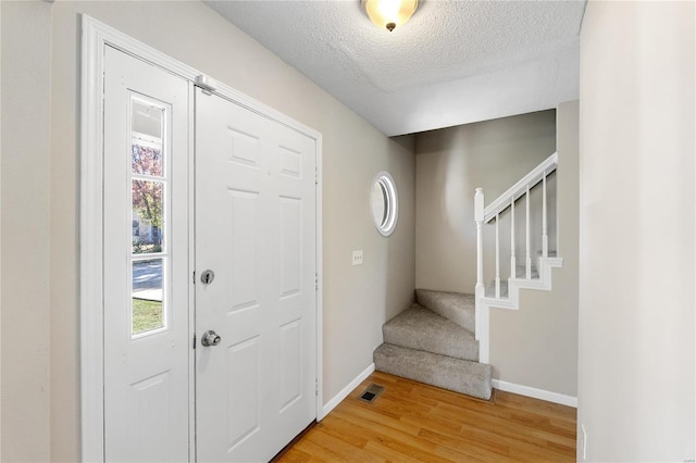 foyer entrance with wood-type flooring and a textured ceiling