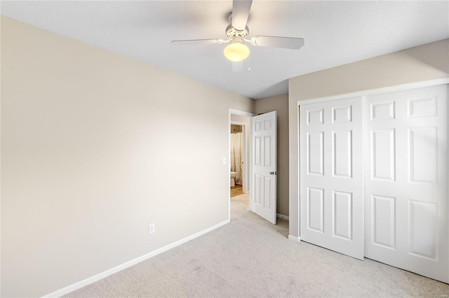 unfurnished bedroom featuring ceiling fan, a closet, and light colored carpet