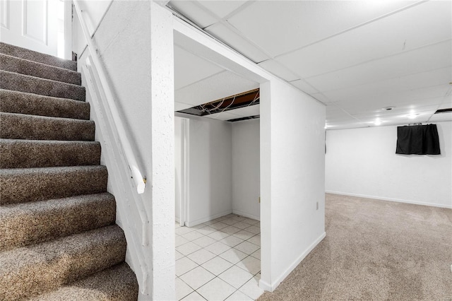 basement with a paneled ceiling and light carpet