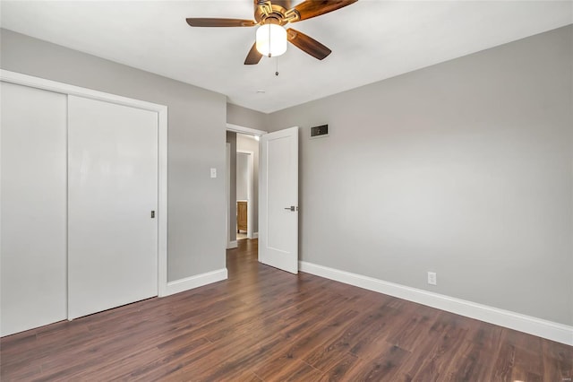 unfurnished bedroom with dark hardwood / wood-style flooring, a closet, and ceiling fan