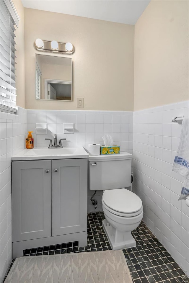 bathroom featuring toilet, vanity, tile walls, and tile patterned flooring