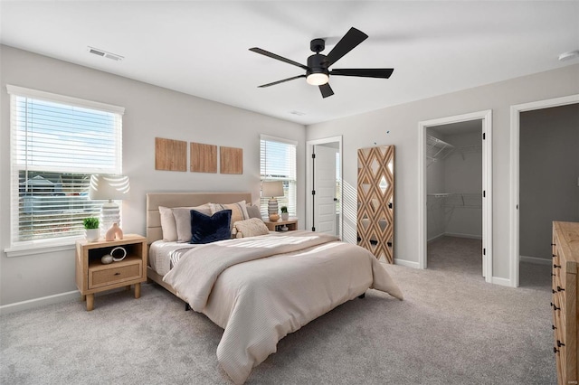 bedroom with ceiling fan, light carpet, a closet, and a spacious closet