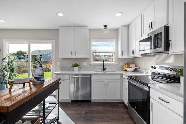 kitchen featuring dark hardwood / wood-style flooring, white cabinetry, a healthy amount of sunlight, and stainless steel appliances