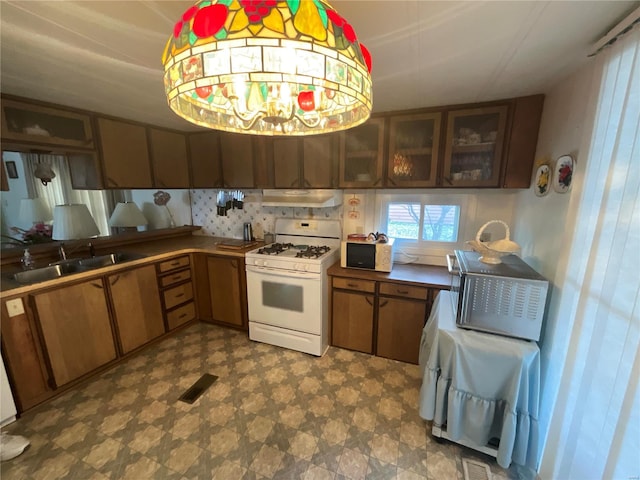 kitchen with gas range gas stove, tasteful backsplash, and sink