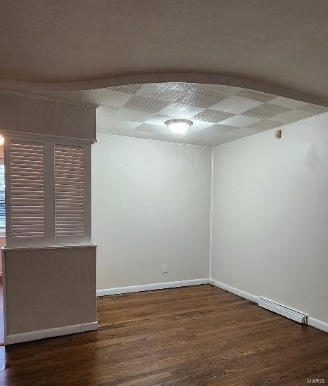 empty room with dark hardwood / wood-style flooring and a baseboard radiator