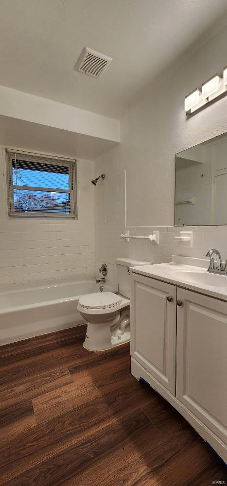 full bathroom featuring hardwood / wood-style floors, vanity, tiled shower / bath, and tasteful backsplash