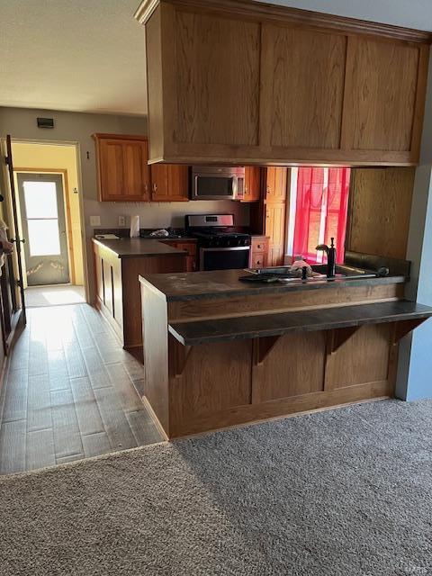 kitchen with appliances with stainless steel finishes, a kitchen bar, dark hardwood / wood-style floors, sink, and kitchen peninsula