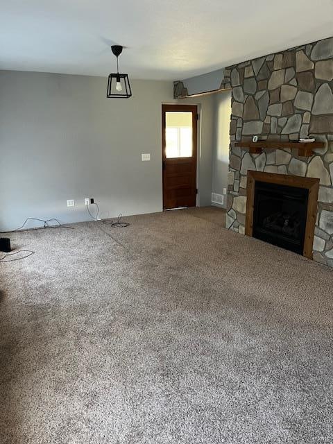 unfurnished living room with carpet flooring and a fireplace