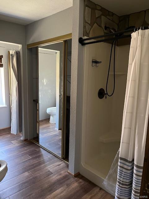 bathroom with a shower with shower curtain, hardwood / wood-style flooring, and toilet