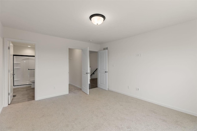 unfurnished bedroom with light colored carpet and connected bathroom