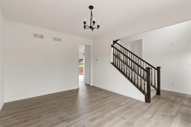 unfurnished living room featuring light wood-type flooring and an inviting chandelier