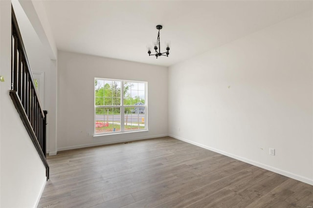 spare room with light hardwood / wood-style floors and a chandelier