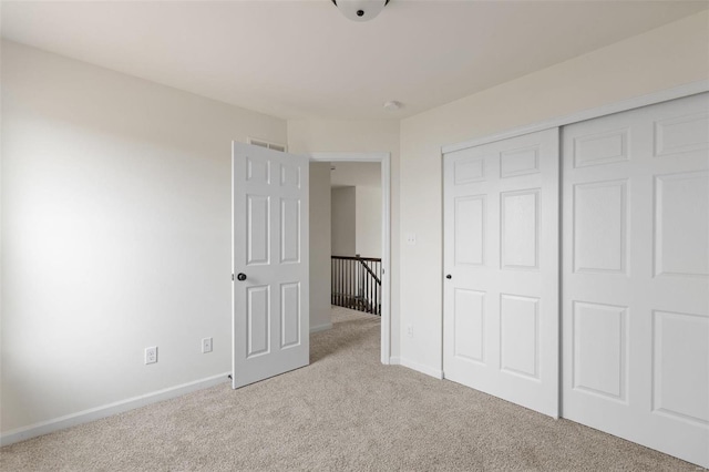 unfurnished bedroom with light carpet and a closet