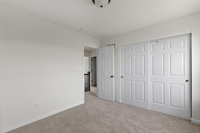 unfurnished bedroom with light carpet and a closet