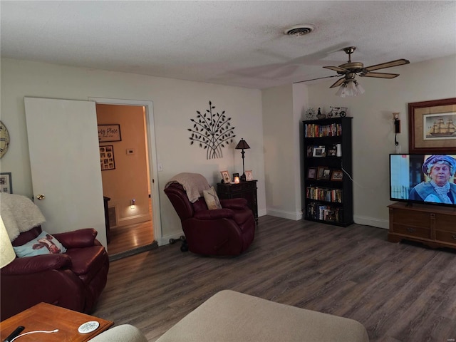 living room featuring a textured ceiling, ceiling fan, and dark wood-type flooring