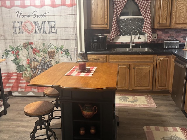 kitchen featuring wood-type flooring, tasteful backsplash, stainless steel dishwasher, and sink