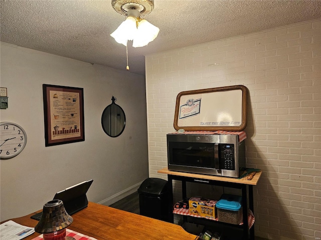 office space featuring ceiling fan, a textured ceiling, and brick wall