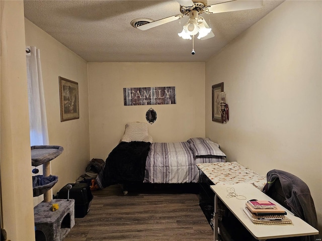 bedroom with ceiling fan, dark hardwood / wood-style floors, and a textured ceiling