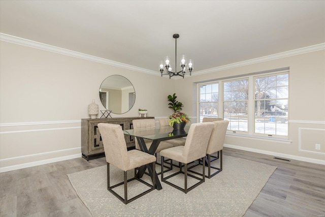 dining room with crown molding, light hardwood / wood-style flooring, and a notable chandelier