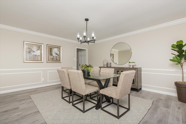 dining space featuring light hardwood / wood-style flooring, ornamental molding, and a notable chandelier