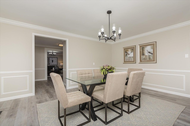 dining space with wood-type flooring, ornamental molding, and a chandelier